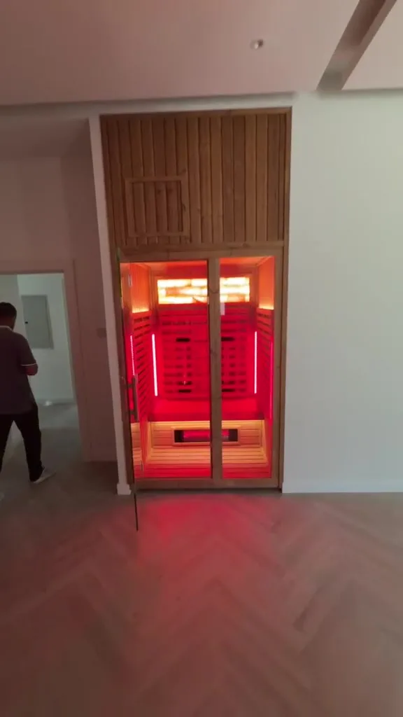 Finished hybrid sauna with full glass front and red light mode, installed by Sauna Spaces in a Dubai villa